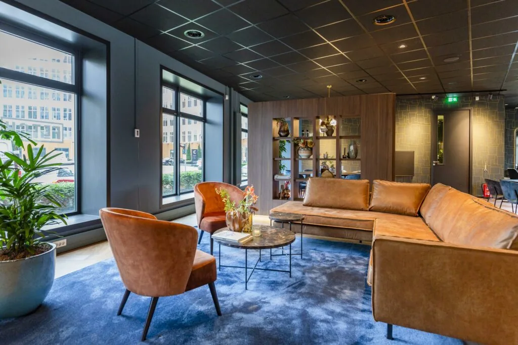 Modern ingerichte wachtruimte aan de George Hintzenweg met leren banken, designstoelen en grote ramen met uitzicht op de straat.